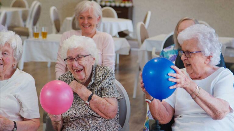 A senior and family member chatting over tea in a cozy assisted living lounge.