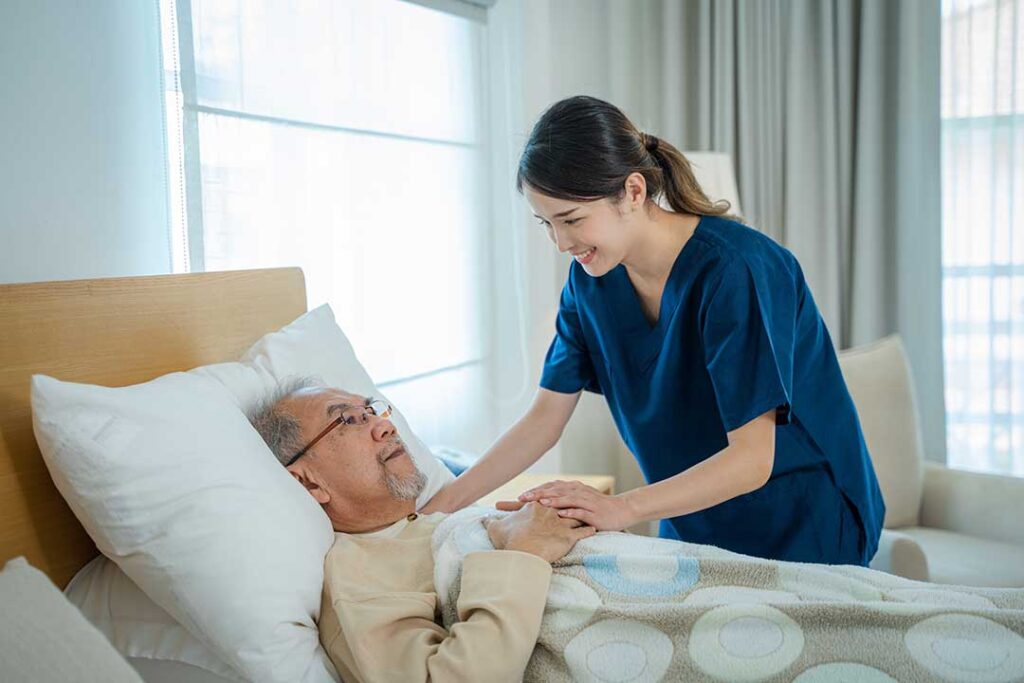 A resident using a tablet with staff assistance in a comfortable common room.