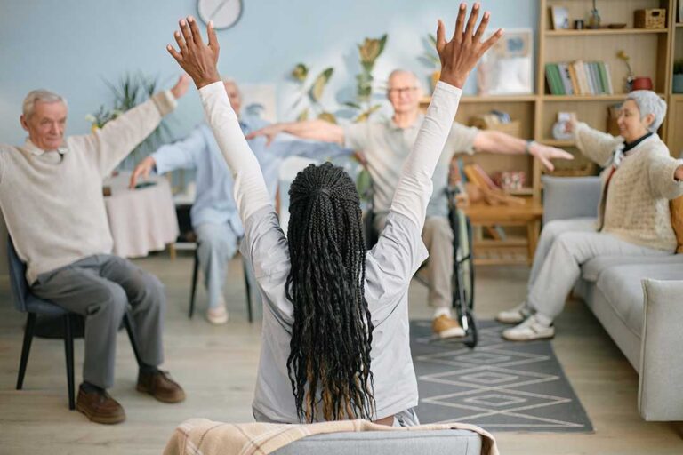 Family members greeting an elderly resident in a comfortable assisted living common area.